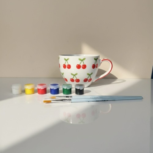 Ręcznie malowana filiżanka we wzór wisienek – inspiracja do zestawu DIY.